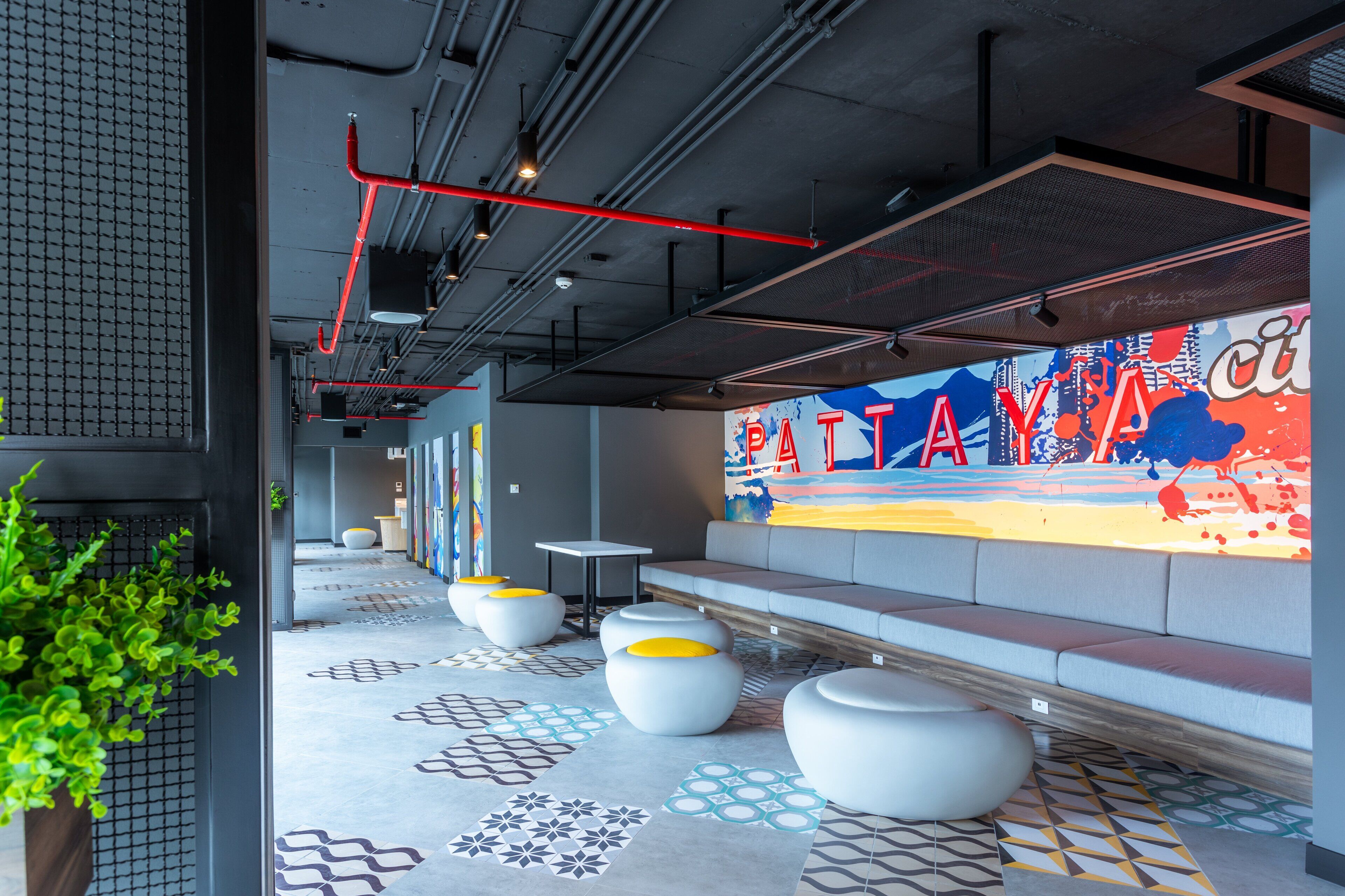 A modern interior with a colorful mural, seating areas, and a patterned floor.