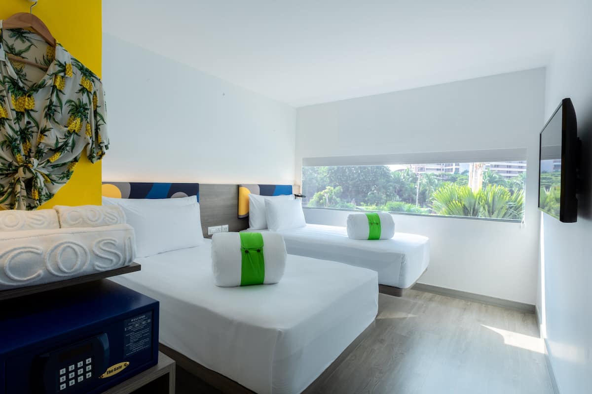 Habitación de hotel con dos camas, televisión y vistas a zonas verdes.