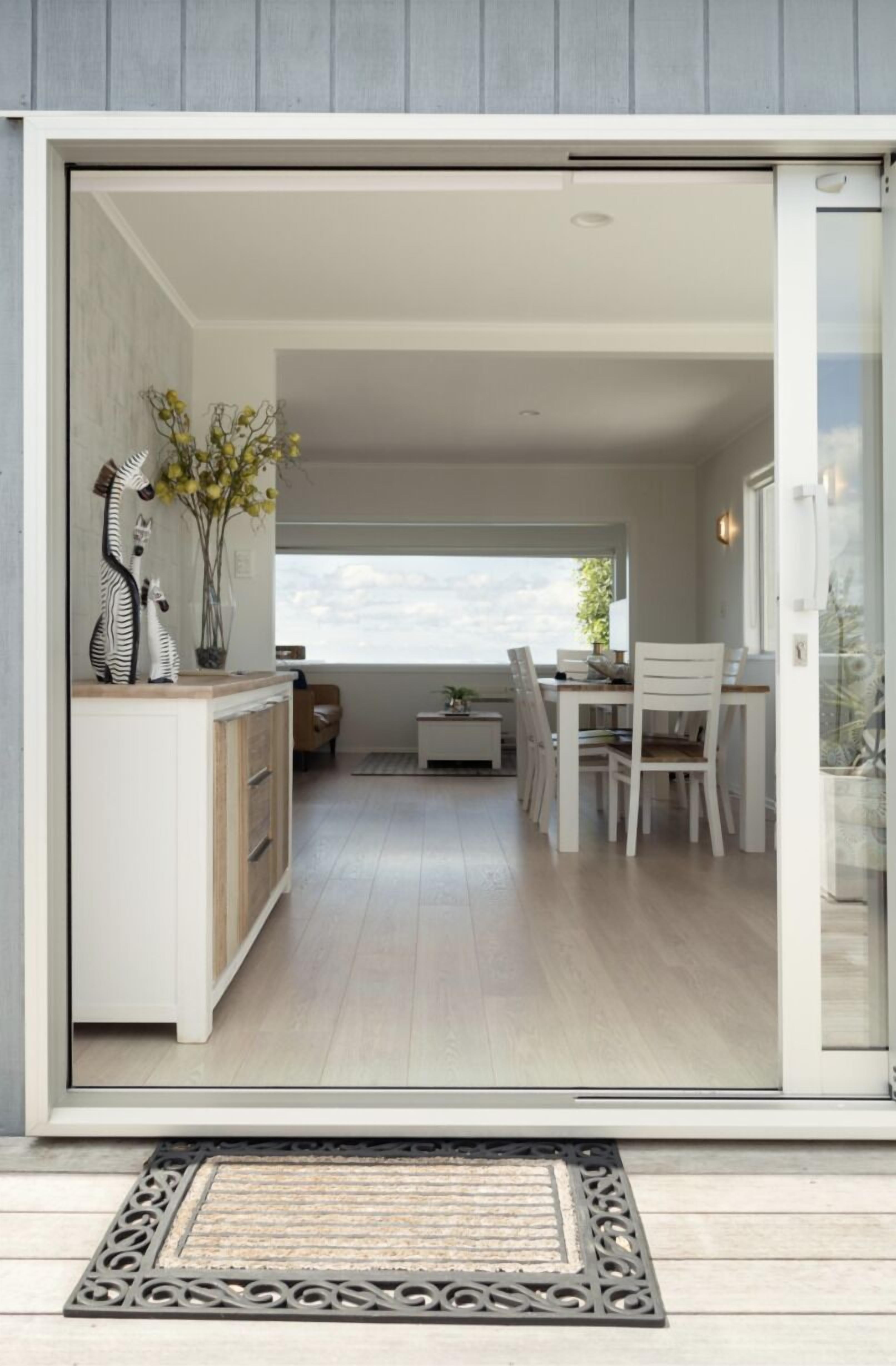 Um interior moderno com uma porta de correr de vidro que dá para uma área de jantar com mesa e cadeiras.