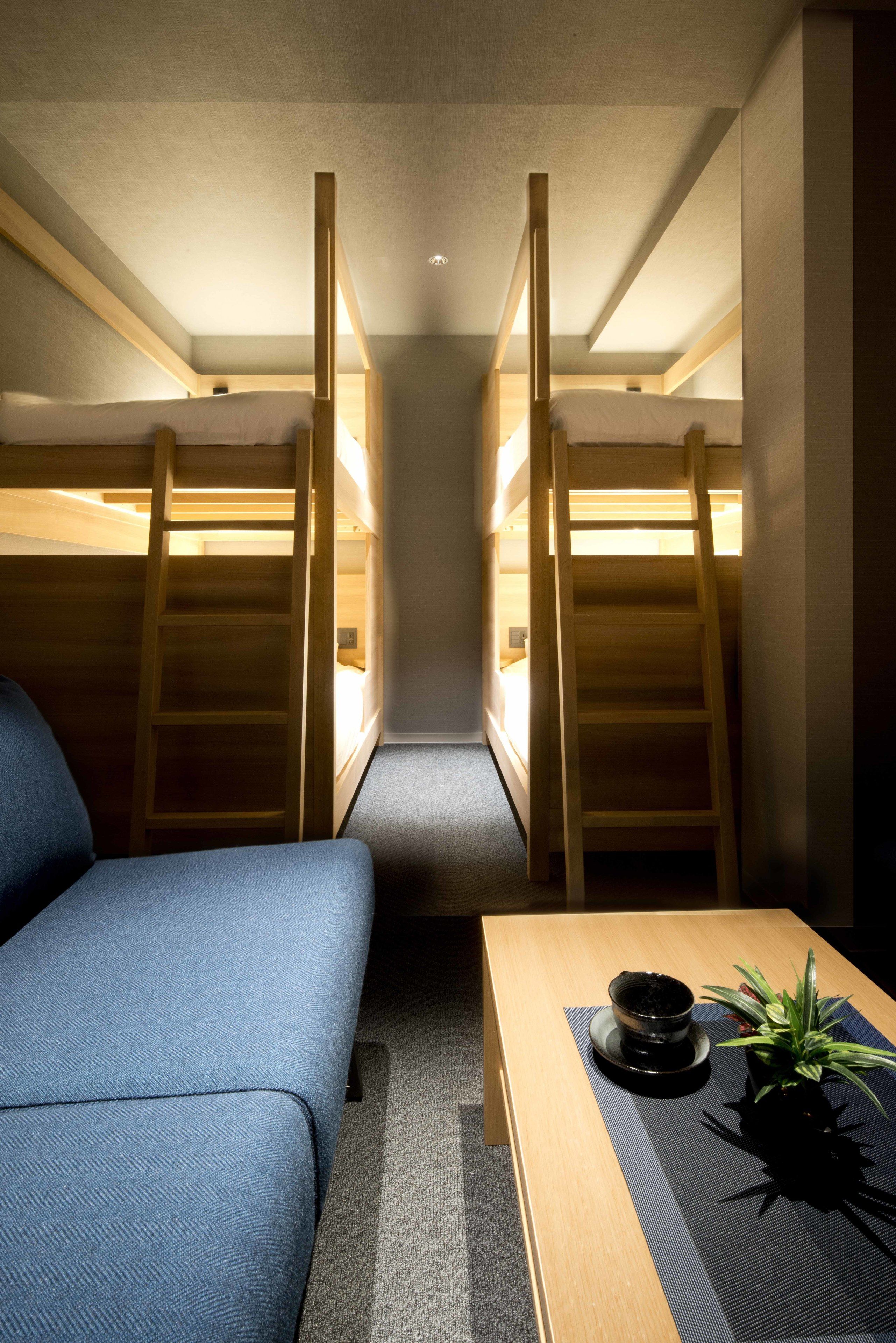 A room with two bunk beds, a sofa, a table with a plant, and a small table with a cup and saucer.