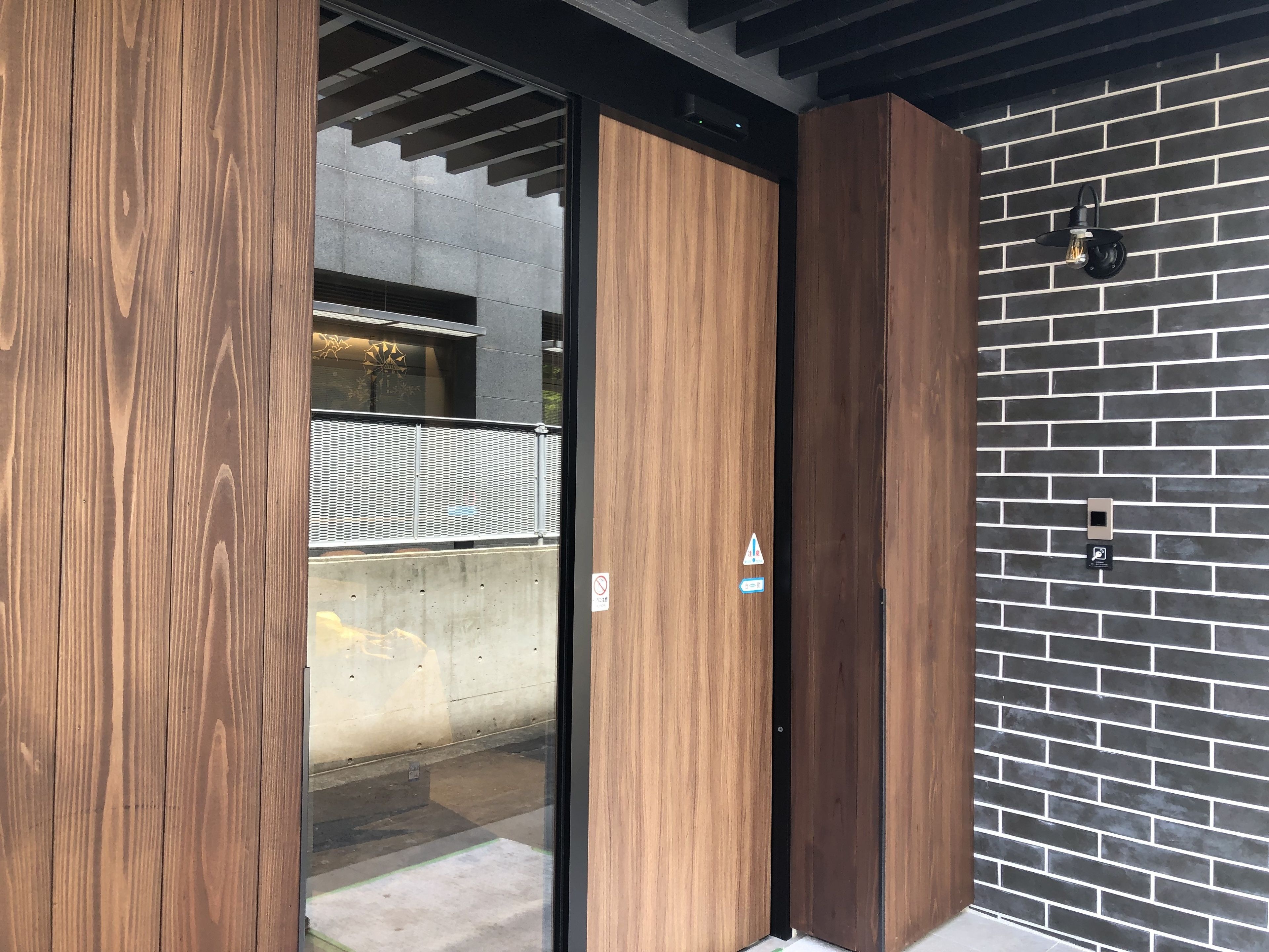 A modern building entrance with a wooden door and a brick wall.