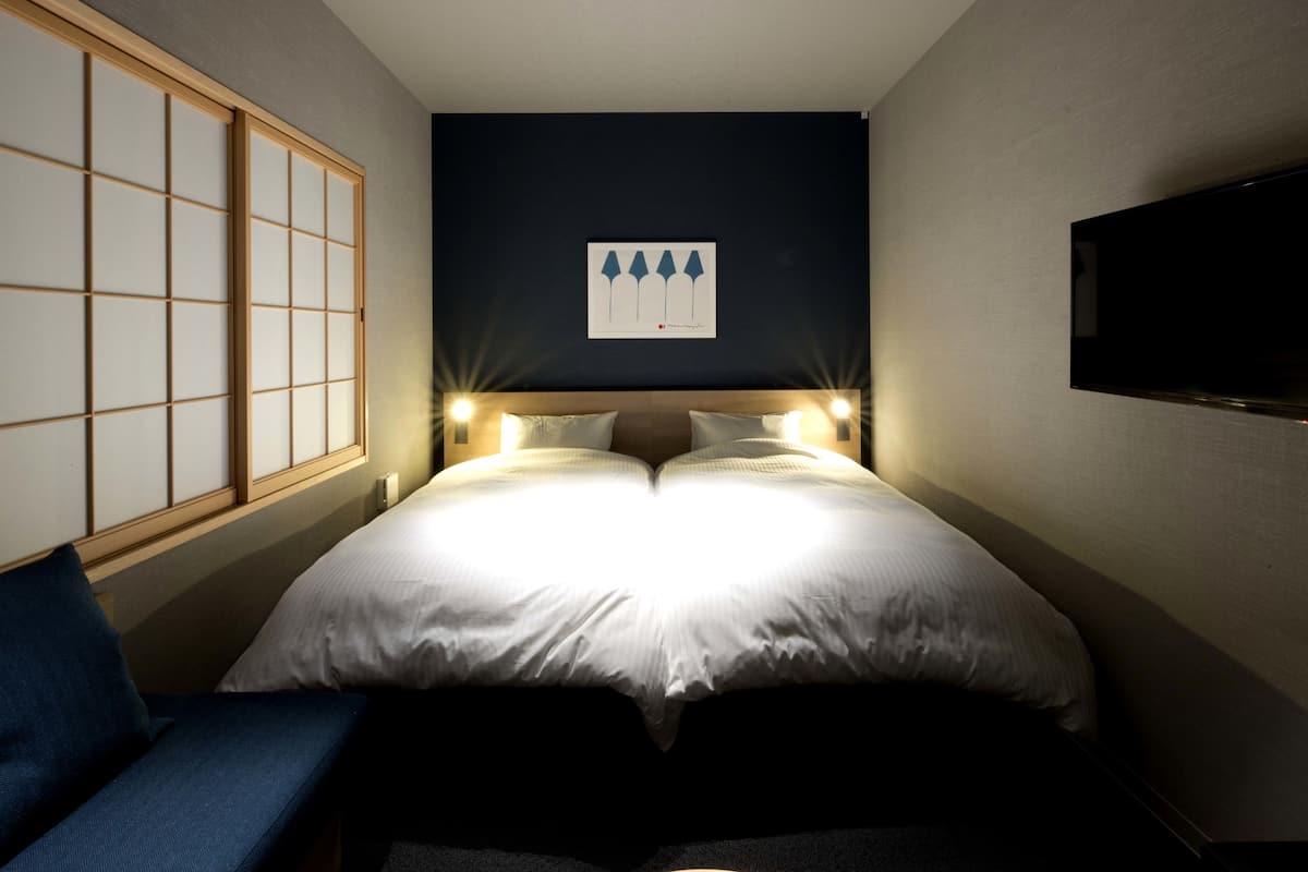 Een hotelkamer met een bed, nachtlampjes, een televisie en een schuifdeur.