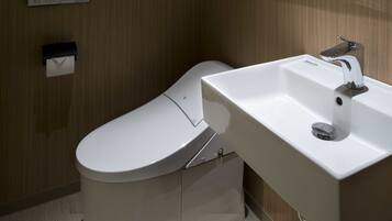 Een moderne badkamer met toilet, wastafel en handdoekdispenser.