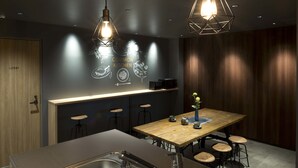 A modern kitchen with a wooden table, bar stools, and pendant lighting.