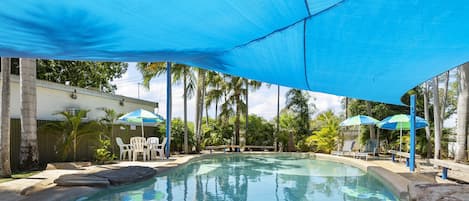 Una piscina al aire libre, sillones reclinables de piscina