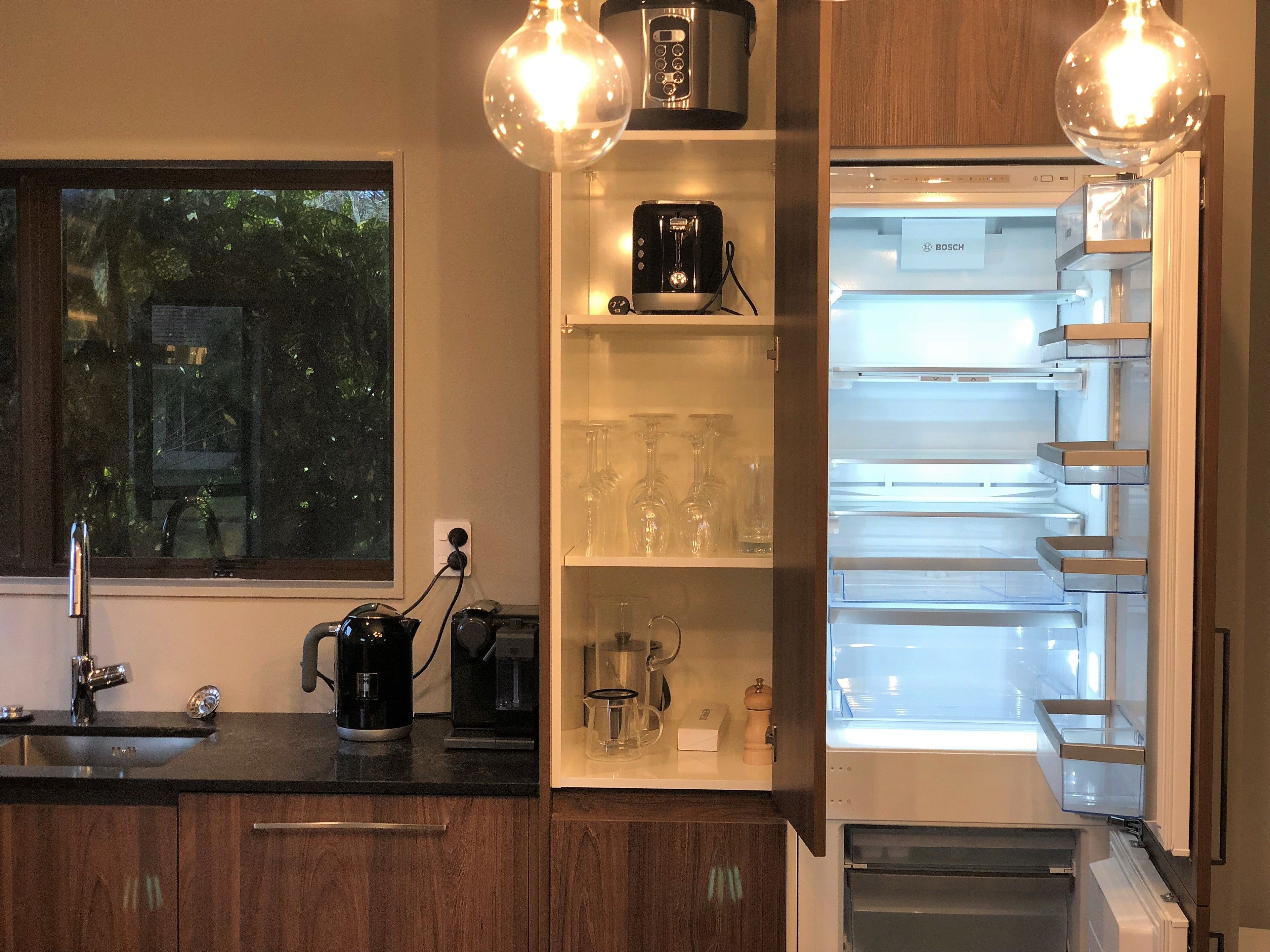 A modern kitchen with a built-in refrigerator, a coffee maker, and a wine glass rack.