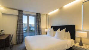 Habitación de hotel con una cama grande, un escritorio y vistas a las montañas desde la ventana.