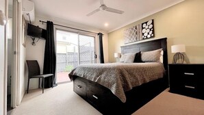 A bedroom with a bed, a chair, a desk, a ceiling fan, and a TV. - Anaheim Park Oasis (Upper Coomera)