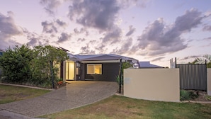 A modern house with a dark exterior, a well-maintained lawn, and a gravel driveway leading to the entrance. - Anaheim Park Oasis (Upper Coomera)