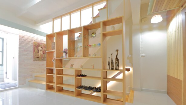 A spacious room with a large wooden bookshelf, a staircase, and a door leading to another area.