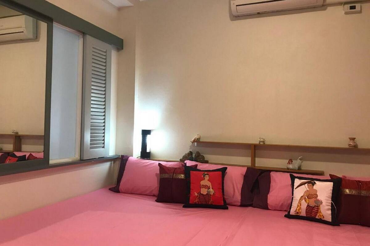 A bedroom with a bed, pillows, a mirror, and a shelf with decorative items.
