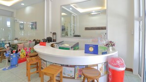 A reception area with a counter, chairs, a mirror, and a trash bin.