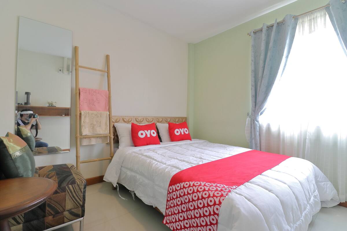 A hotel room with a bed, a wooden ladder, a chair, and a table.