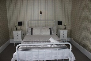 Eenvoudige tweepersoonskamer | Een strijkplank/strijkijzer, beddengoed