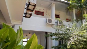 Een gebouw met meerdere verdiepingen, balkons, grote ramen en kamerplanten.