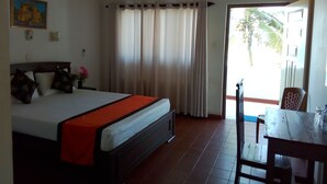 Een slaapkamer met een bed, gordijnen, een plafondventilator, een tafel en een stoel.