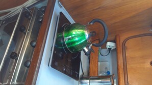 Una cucina con un fornello, un bollitore verde e un lavandino.