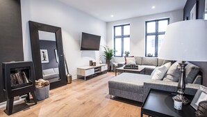 Un salon moderne avec une cheminée, un canapé et un téléviseur.