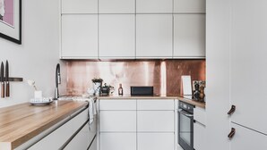 Une cuisine moderne avec des meubles blancs, un plan de travail en bois et un revêtement mural en cuivre.