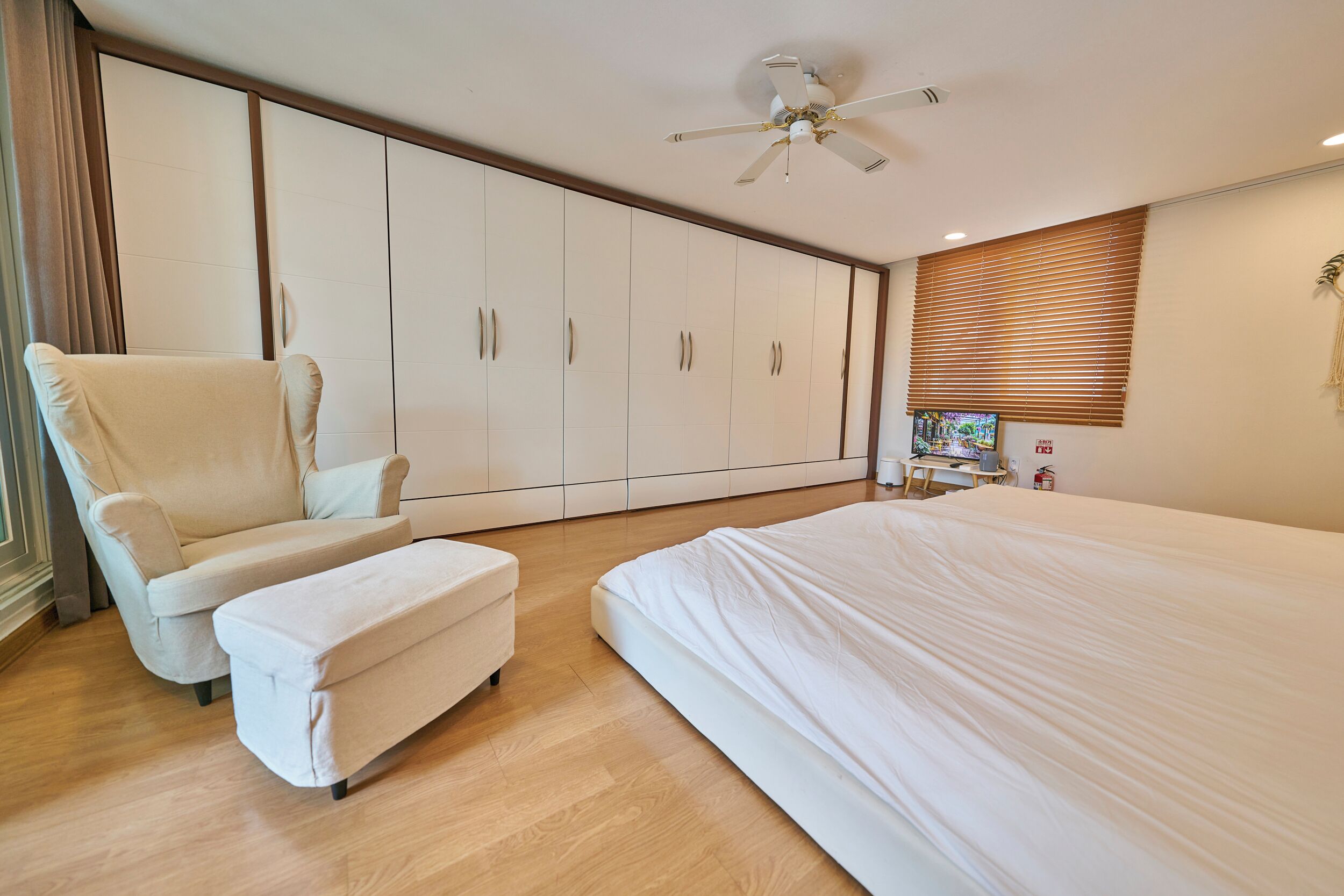 Un dormitorio con una cama grande, una silla, una mesita y un armario.