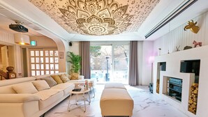 A spacious living room with a large sofa, a small table, and a fireplace. - SG Tailored Serviced Home 5min walk from metro (Seoul)