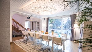 A dining area with a long table, white chairs, and a patterned rug. - SG Tailored Serviced Home 5min walk from metro (Seoul)