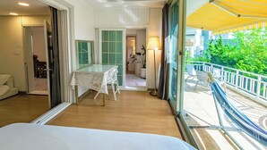 A hotel room with a balcony, a bed, a table with a lace tablecloth, and a view of the outside. - SG Tailored Serviced Home 5min walk from metro (Seoul)