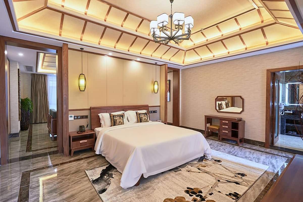 Ein modernes Hotelzimmer mit einem großen Bett, Nachttischen, einem Spiegel und einer Chandelier.