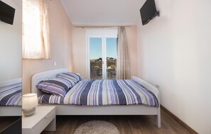 Une chambre à coucher avec un lit, une table de chevet, une lampe et une vue sur l’extérieur par une fenêtre.