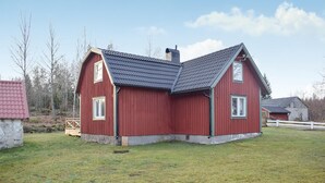 Une grange rouge avec un toit en pente, une cheminée et deux fenêtres.