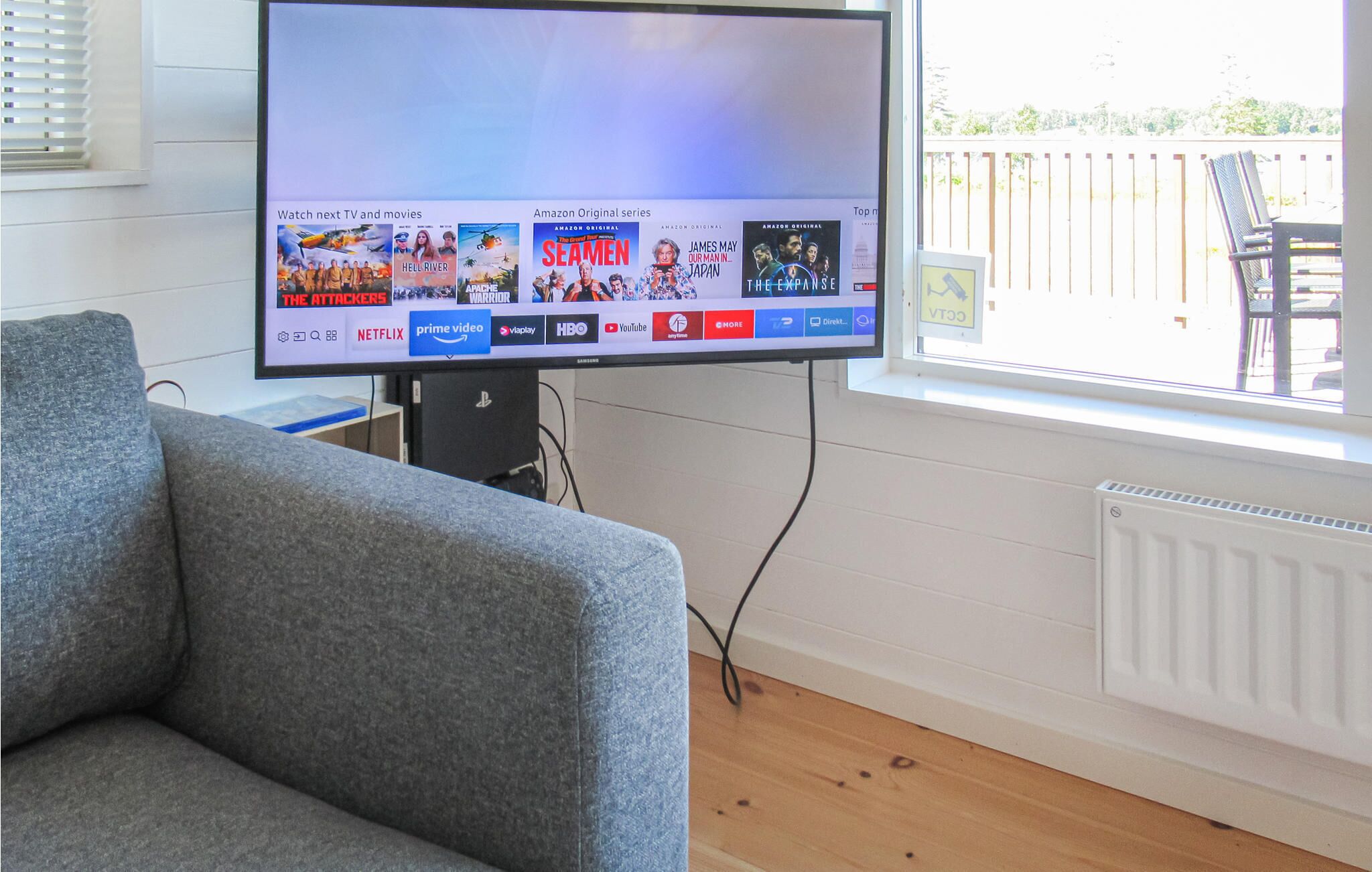 A flat-screen TV mounted on a wall displaying a streaming service interface with various TV shows and movies.