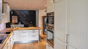 Una cocina moderna con armarios blancos, encimera de madera y horno empotrado.