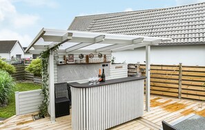 A patio with a built-in bar, outdoor seating, and a pergola.
