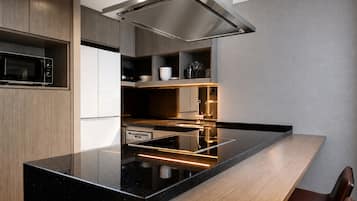 A modern kitchen with a black countertop, stainless steel appliances, and wooden cabinetry.