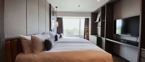 A modern hotel room with a large bed, a flat-screen TV mounted on the wall, and a view of the outdoors through the window.