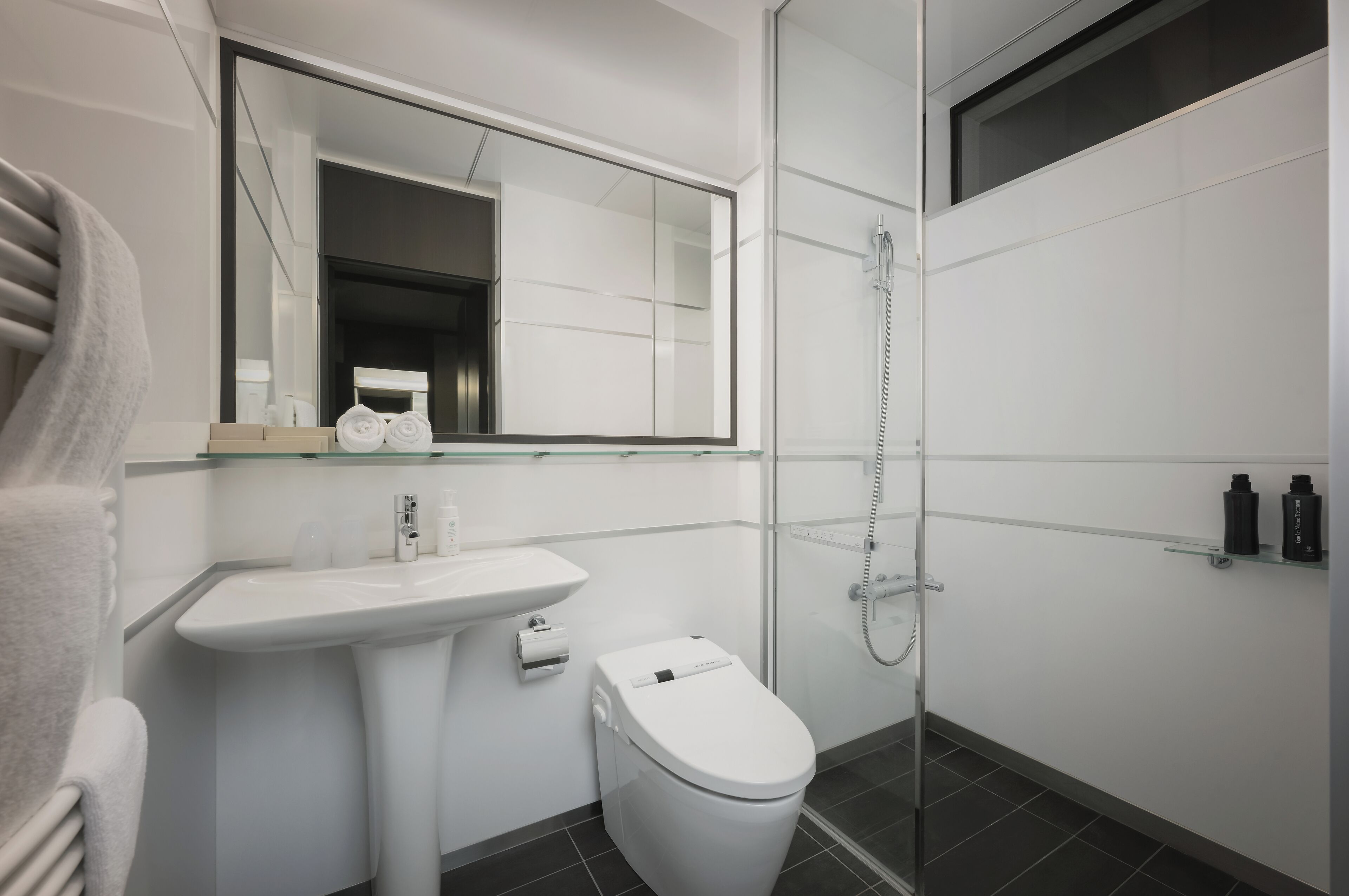 A modern bathroom with a white sink, toilet, and glass shower enclosure.