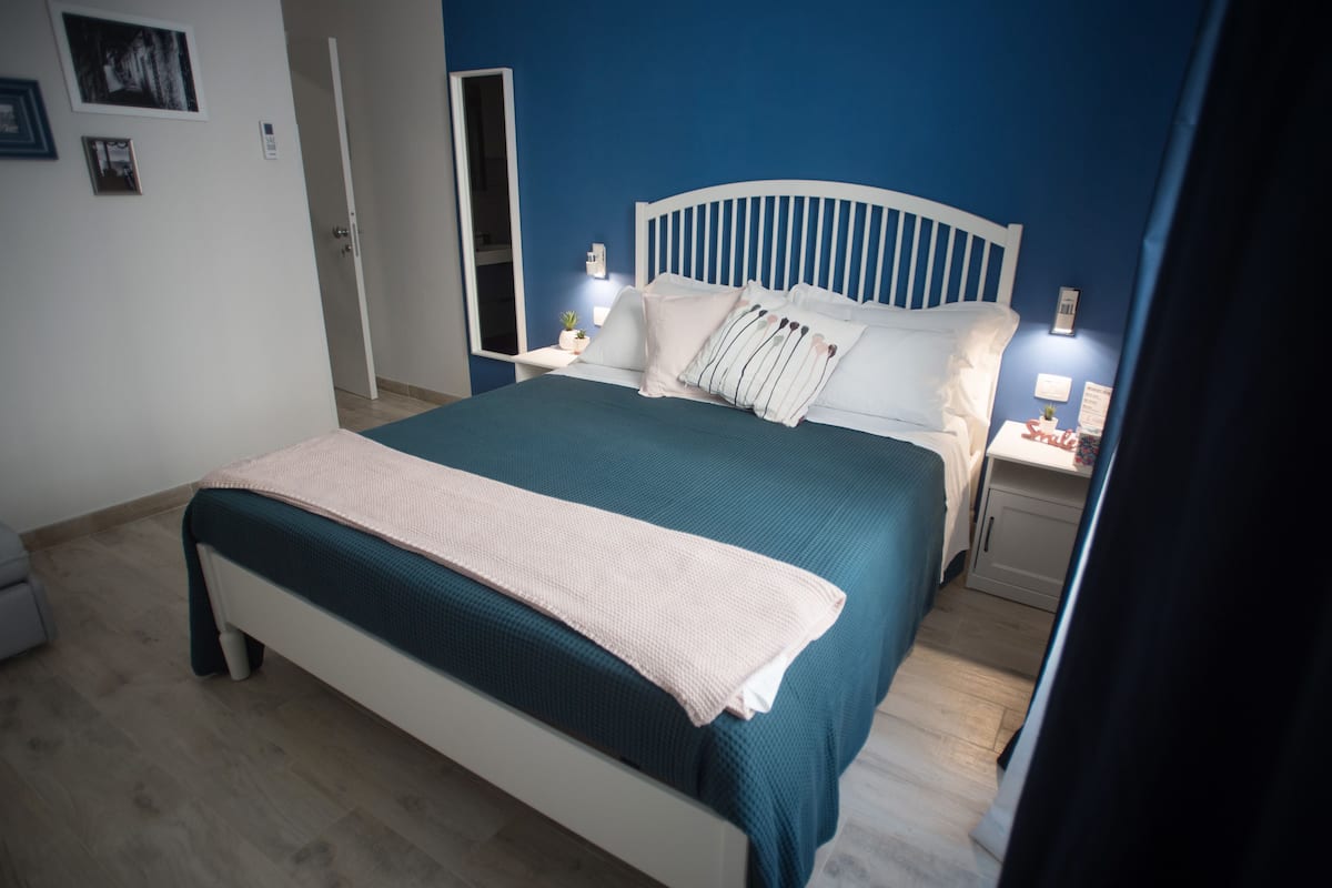A bedroom with a bed, nightstands, and a mirror.