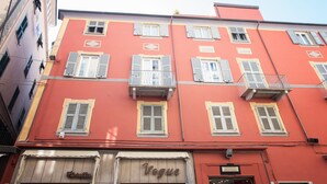 Un edificio rojo con varias ventanas, un balcón y un escaparate que dice "Vogue".
