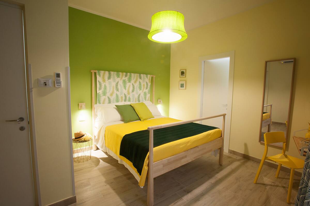 A bedroom with a bed, a chair, a mirror, and a door.