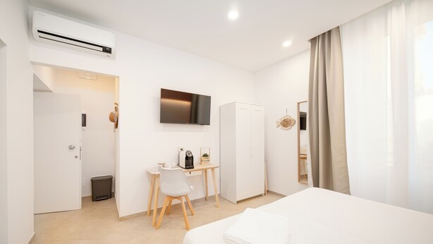 Una habitación de hotel con cama, escritorio, silla, armario y televisor.