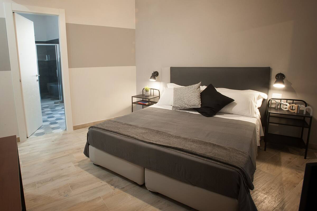 A bedroom with a bed, bedside tables, and a nightstand.