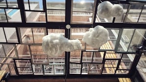 A high-rise building with large windows and three fluffy white clouds hanging inside. - GOIN Old House & Bar (Tainan)