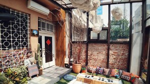 A cozy outdoor seating area with a brick wall, a wooden door, and a glass enclosure. - GOIN Old House & Bar (Tainan)
