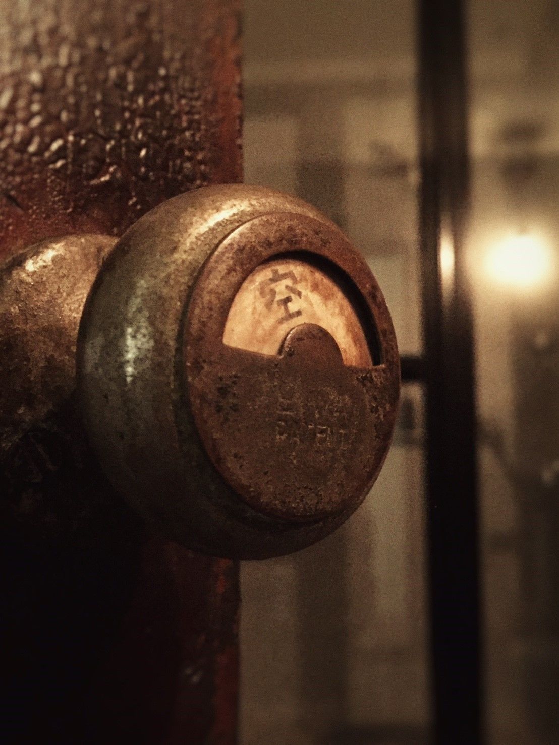 A close-up of a rusty metal valve with a circular handle, set against a blurred background.