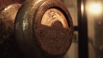 A close-up of a rusty metal valve with a circular handle, set against a blurred background.