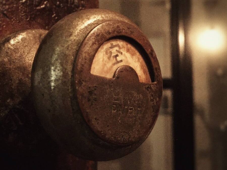 A close-up of a rusty metal valve with a circular handle, set against a blurred background.
