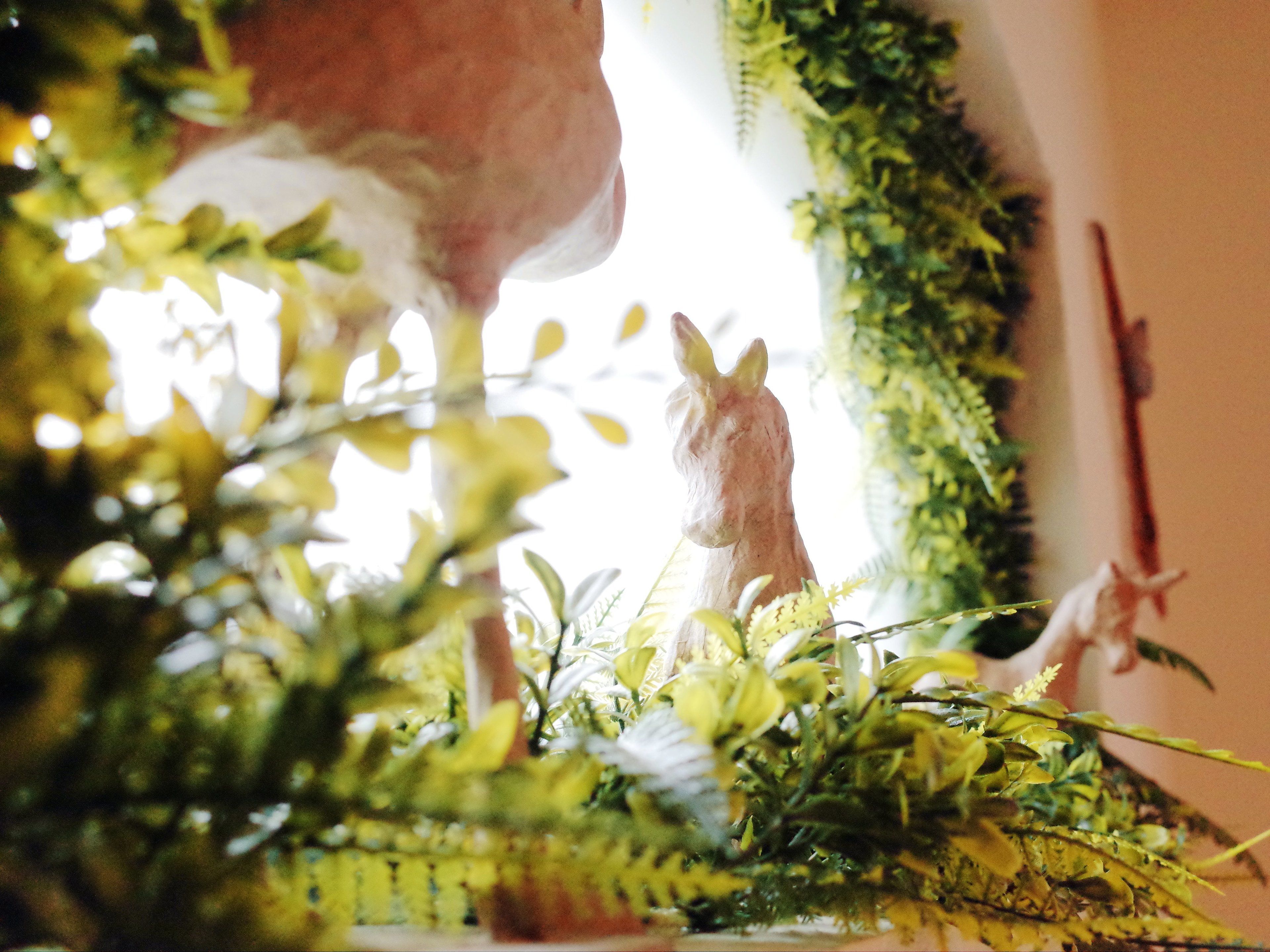 A room with a large window, a decorative horse figurine, and various indoor plants.