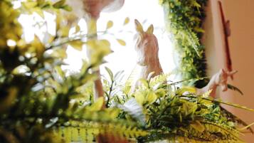 A room with a large window, a decorative horse figurine, and various indoor plants.