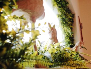 A room with a large window, a decorative horse figurine, and various indoor plants.