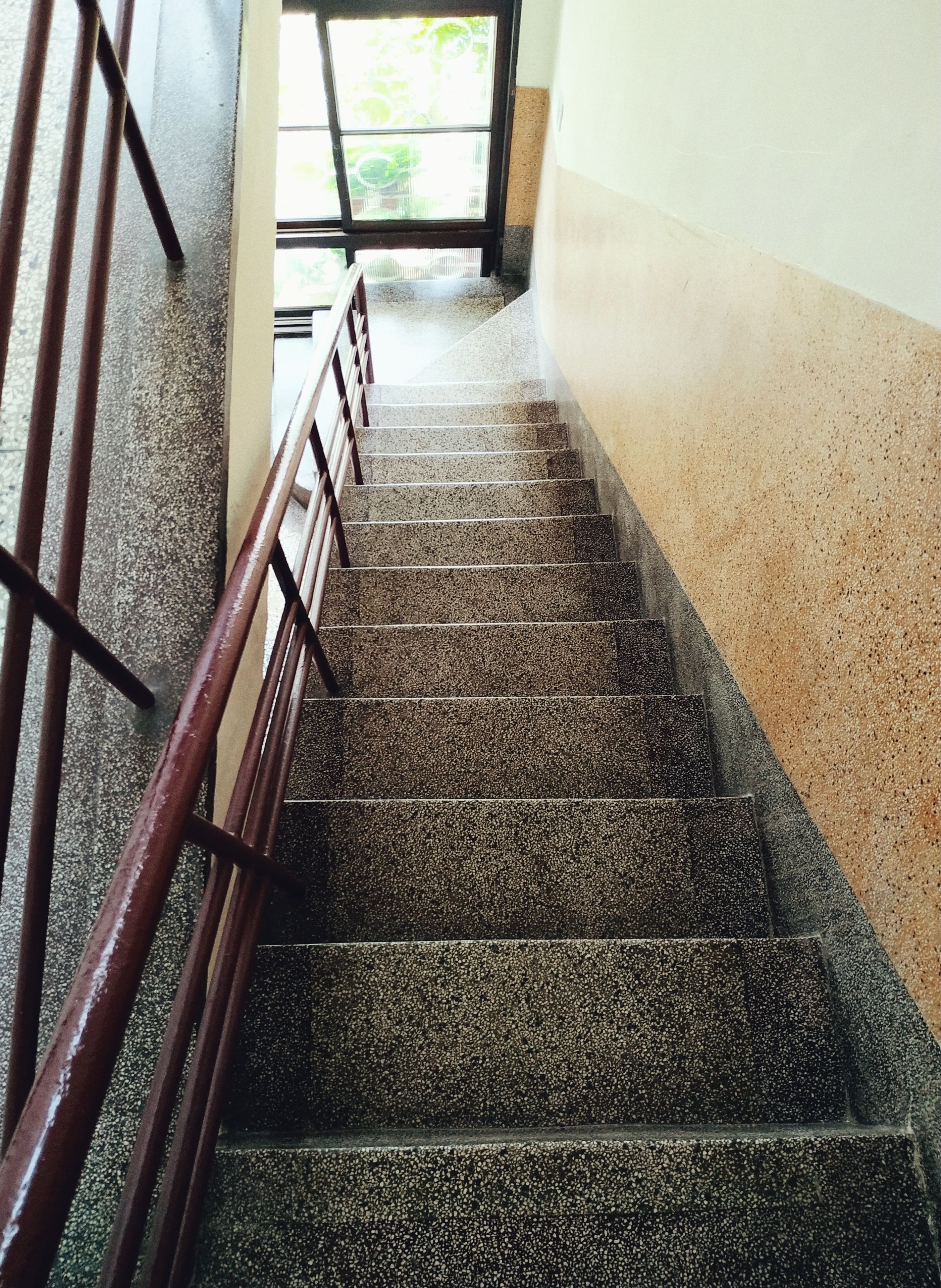 Una escalera con barandilla metálica que lleva a un espacio exterior.